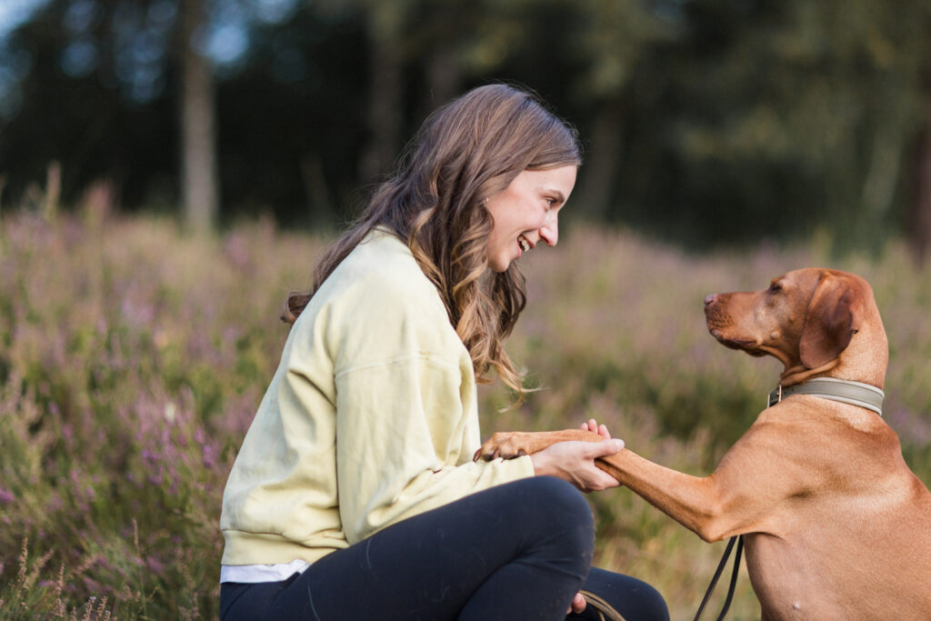 Hundetraining Münster: Frau hält die Pfote des Hundes als Symbol für Vertrauen und Verhaltensberatung.